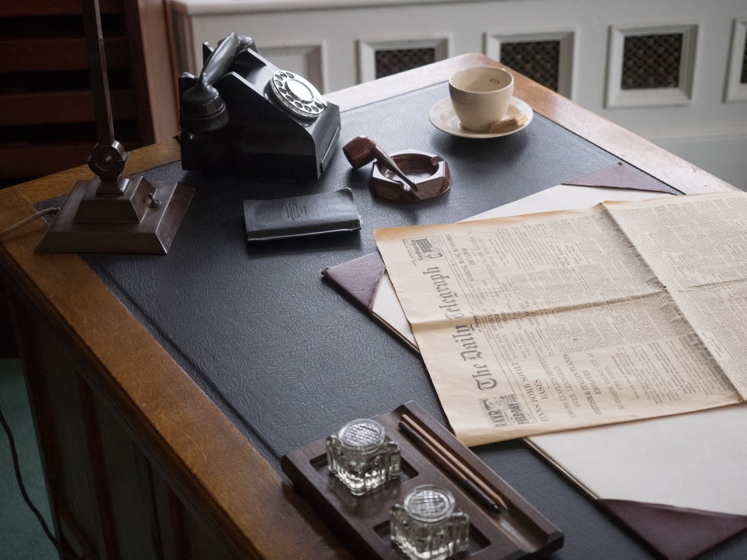 Schreibtisch mit ausgebreiteten Zeitungsseiten, Notizbuch und Stift in der Draufsicht